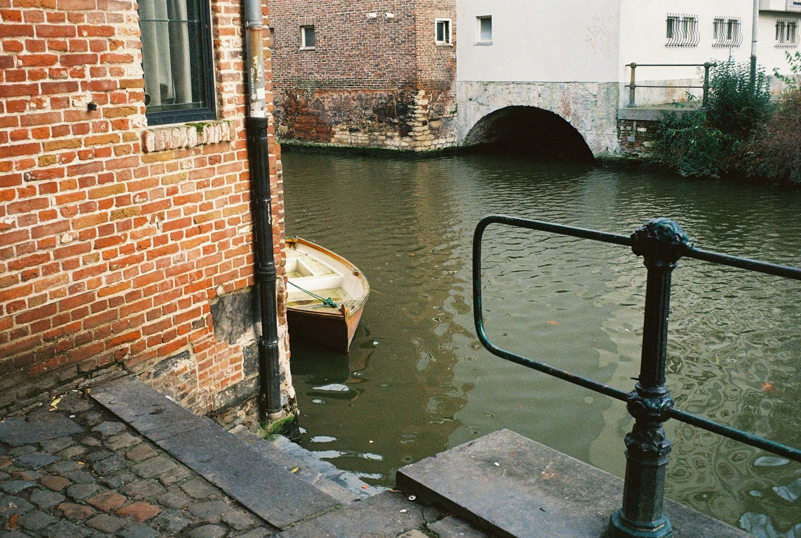 Bakstenen gevels aan het water met een roeibootje en een brugje