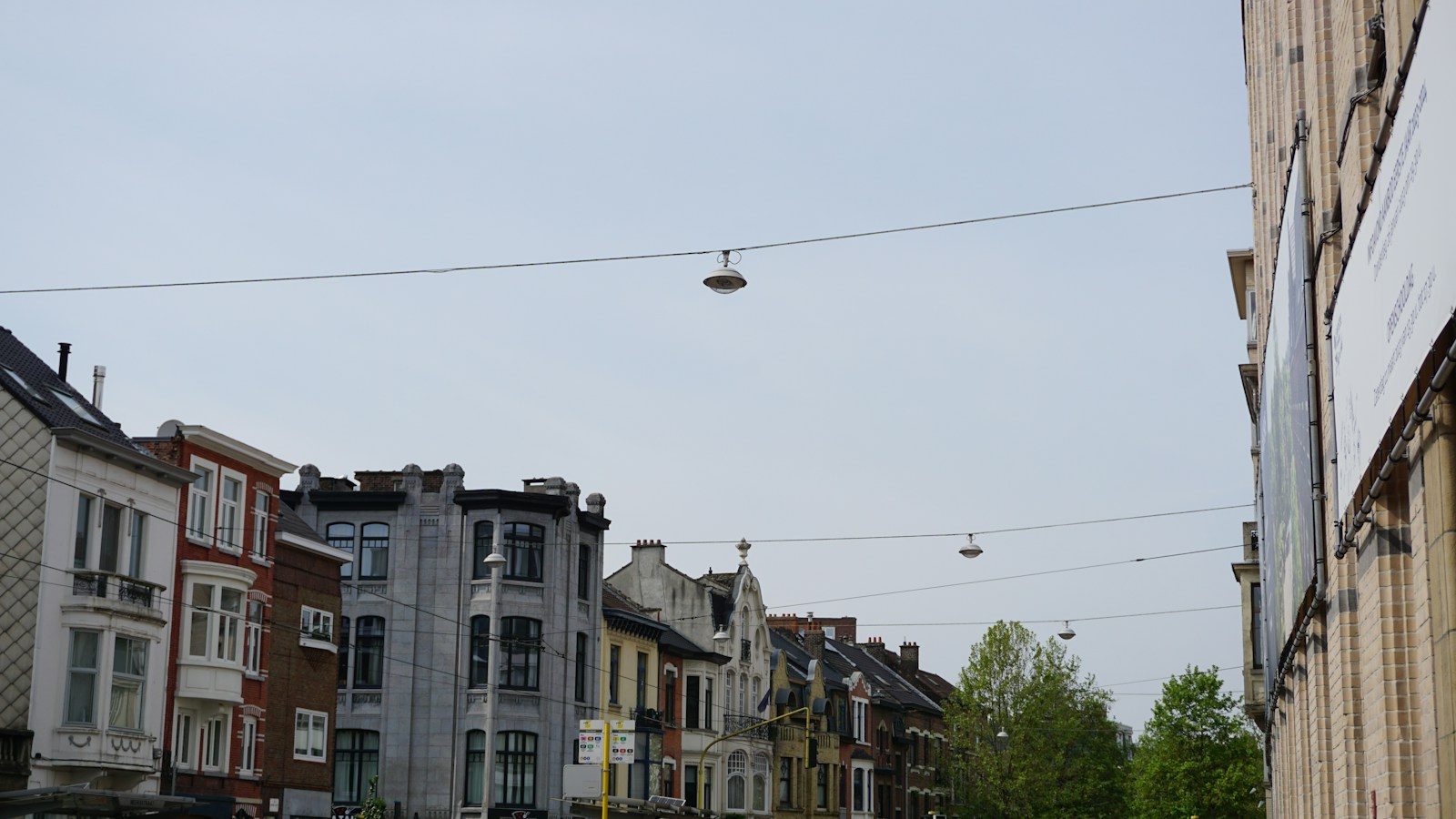 Straat met rijwoningen met gepleisterde en bakstenen gevels onder een grijze lucht